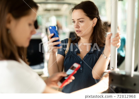 Brunette with smartphone in bus 72812968