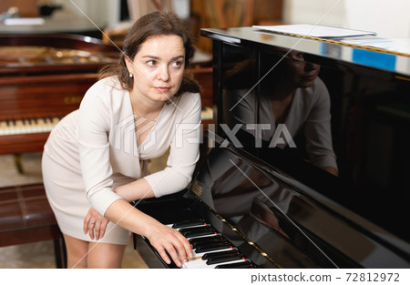 Beautiful girl chooses a piano in a music store Beautiful girl chooses a piano in a music store 72812972