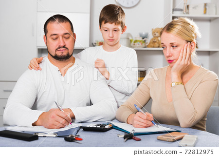 Tense parents with sad son writing documents Tense parents with sad son writing documents 72812975