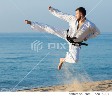 Man doing karate at ocean 72813097