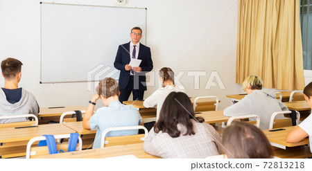 Teacher explaining studying material to teenagers during lesson 72813218