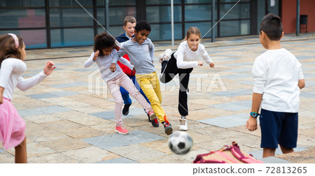 Group of tweenagers playing football in school yard after lessons Group of tweenagers playing football in school yard after lessons 72813265