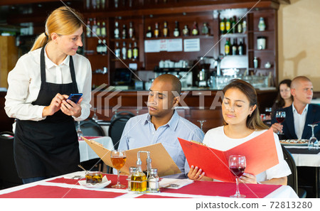 Positive couple making order with waitress in pizza restaurant Positive couple making order with waitress in pizza restaurant 72813280