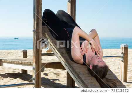Woman training on fitness station on beach 72813372