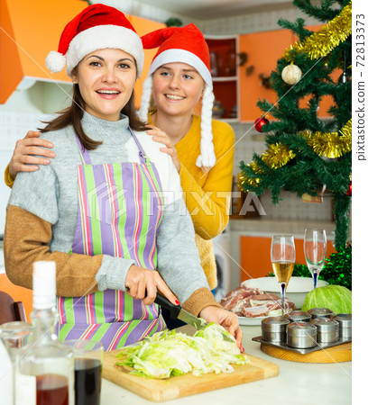 Two young women friends in xmas hats cooking christmas dinner 72813373