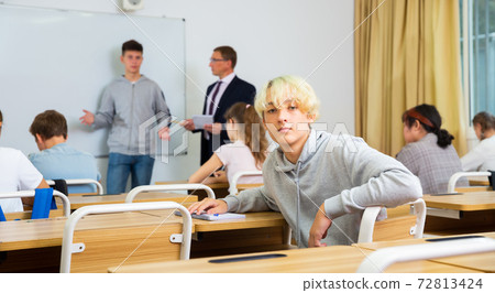 Young teenager is sitting at the desk in classroom Young teenager is sitting at the desk in classroom 72813424