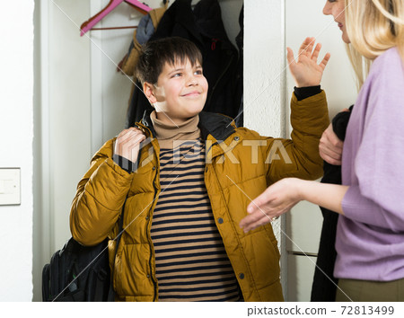 Young woman and son in jacket chatting near door indoors Young woman and son in jacket chatting near door indoors 72813499