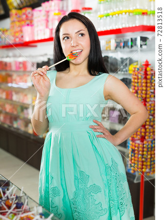 Smiling girl sucking lollypop in store Smiling girl sucking lollypop in store 72813518