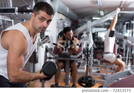 Man exercising with dumbbells in gym 72813573