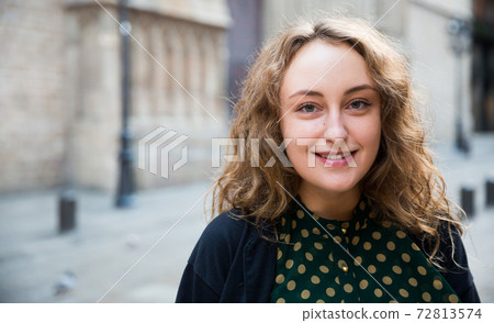 Smiling young woman standing at the street among architecture in Barcelona Smiling young woman standing at the street among architecture in Barcelona 72813574