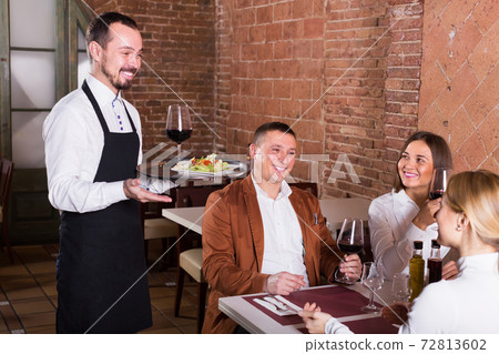 cheerful waiter placing order in front of guests cheerful waiter placing order in front of guests 72813602