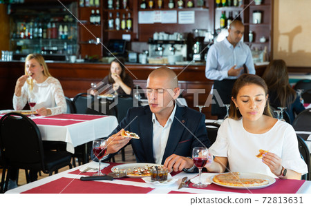 Loving cheerful positive pair enjoying pizza and conversation at restaurant Loving cheerful positive pair enjoying pizza and conversation at restaurant 72813631