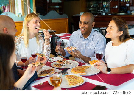 Group of happy people eating pizza with wine in restaurant Group of happy people eating pizza with wine in restaurant 72813650
