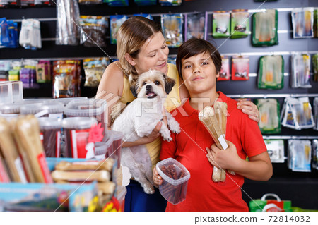 Cheerful woman with preteen son buying dog treats and chews in store to reward their precious pup Cheerful woman with preteen son buying dog treats and chews in store to reward their precious pup 72814032