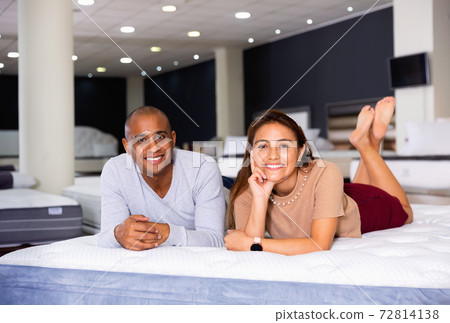 Man and woman choosing mattress in store trying it Man and woman choosing mattress in store trying it 72814138
