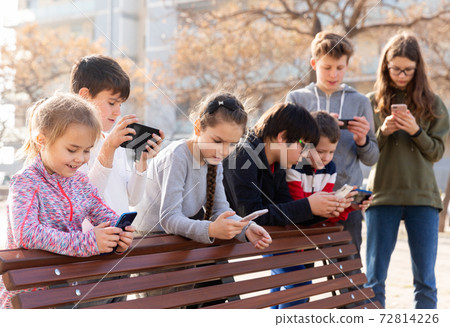 Children are playing on smartphone in the playground Children are playing on smartphone in the playground 72814226