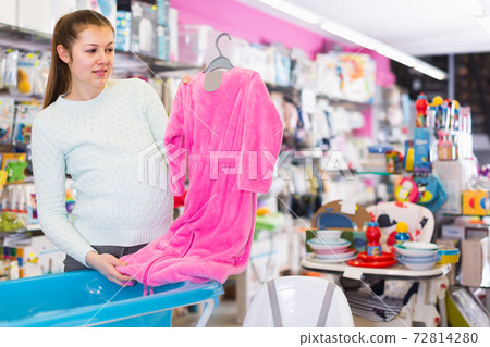 young pregnant female is buying clothes for baby in thestore 72814280