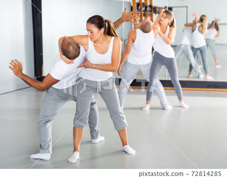 Latina practicing basic self defense movements with male partner Latina practicing basic self defense movements with male partner 72814285