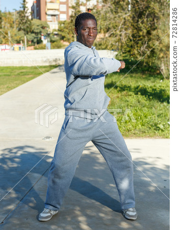 Athletic young male in sportswear training different exercises at park Athletic young male in sportswear training different exercises at park 72814286