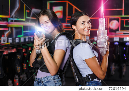 Girl took aim and holding guns during laser tag game in dark lab 72814294