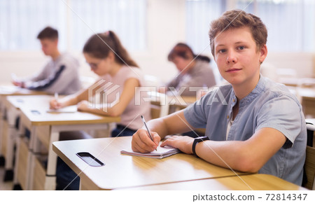 Teen boy sitting at desk in classroom Teen boy sitting at desk in classroom 72814347