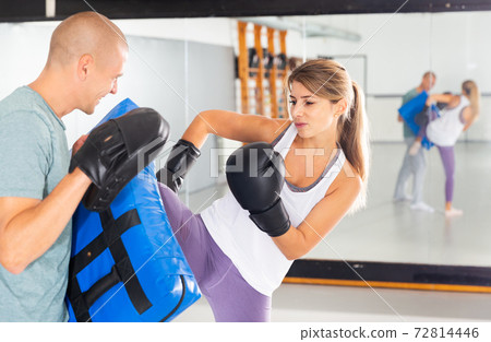 Woman practicing foot strikes on kick shield Woman practicing foot strikes on kick shield 72814446