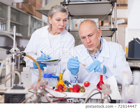 Scientists taking notes while performing experiments Scientists taking notes while performing experiments 72814447