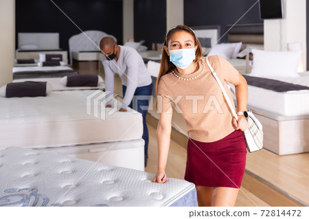 Female wearing protective mask choosing mattress Female wearing protective mask choosing mattress 72814472