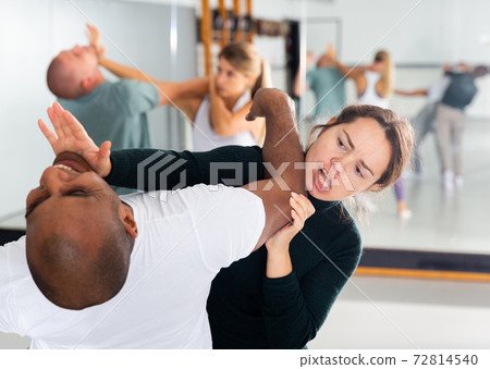 Expressive woman practicing palm heel strike during self-defense training Expressive woman practicing palm heel strike during self-defense training 72814540