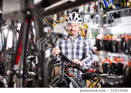 Man in helmet examining a selected bike 72814566