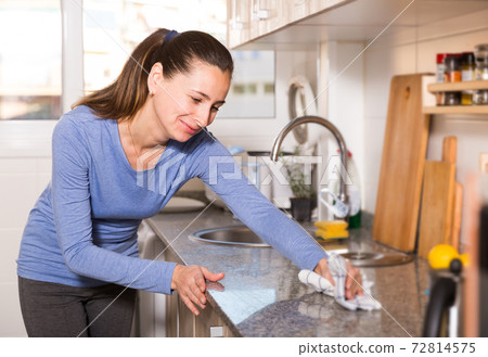 Smiling woman is cleaning surface on the kitchen at the home 72814575