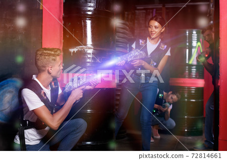 Young friends with laser guns playing laser tag game in dark Young friends with laser guns playing laser tag game in dark 72814661