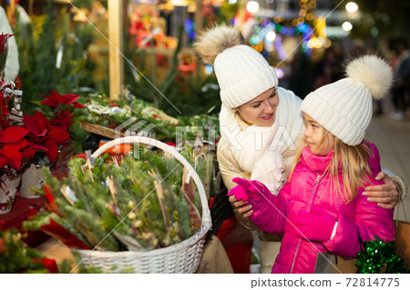 Cheerful girl with mom choosing New Year tree Cheerful girl with mom choosing New Year tree 72814775