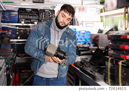Positive male is standing with new impact wrench in tools store 72814913