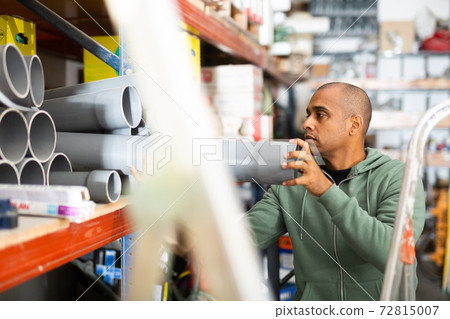 Hispanic man looking for construction supplies in building hypermarket Hispanic man looking for construction supplies in building hypermarket 72815007