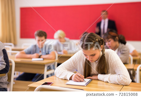 Teen girl sitting at desk in classroom Teen girl sitting at desk in classroom 72815008