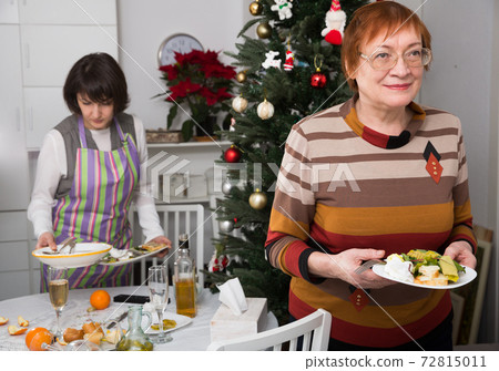 Mature woman clearing table with daughter 72815011
