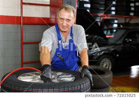 Professional car mechanician inflating tyre Professional car mechanician inflating tyre 72815025