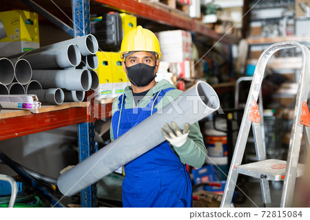 Craftsman in protective mask with plumbing pipe at hardware store 72815084