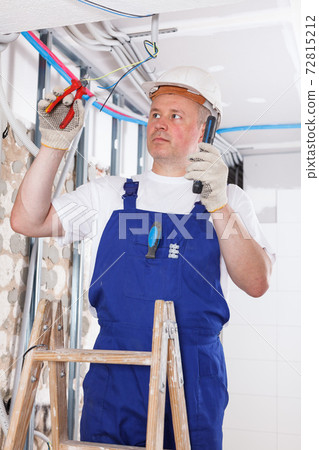 Builder engaged in electrical installation work Builder engaged in electrical installation work 72815212