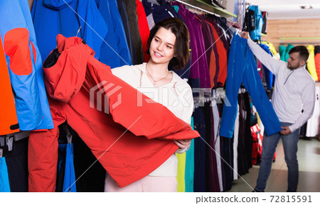 Young attractive brunette looking for winter sport clothing for skiing in shop 72815591