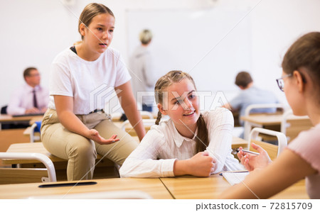 Teenage schoolgirls friendly talking during recess in classroom 72815709