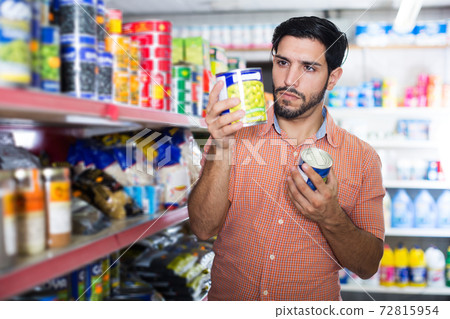 Man is choosing canned peas Man is choosing canned peas 72815954