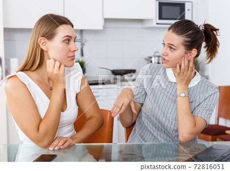 Young emotional girlfriends chatting and looking betrothal ring at home Young emotional girlfriends chatting and looking betrothal ring at home 72816051