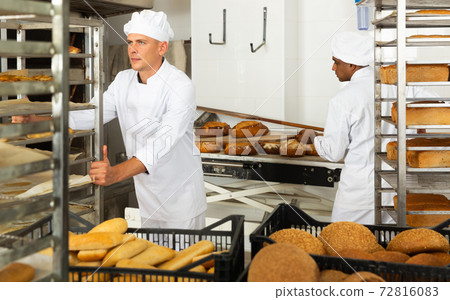 Male baker carrying rack trolley with bread Male baker carrying rack trolley with bread 72816083