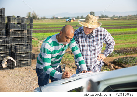 Two male farmers signing papers on farm 72816085