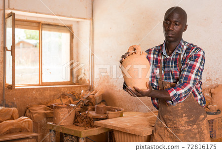 Craftsman examining handmade earthenware 72816175