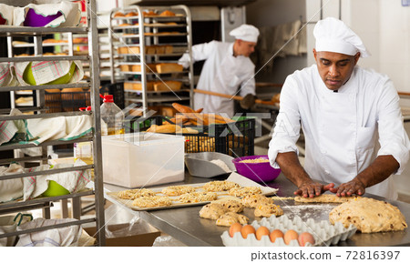 Male baker working with dough forming baguettes 72816397