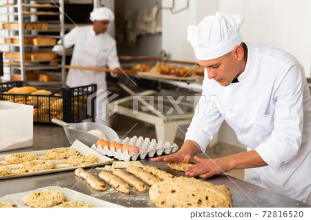 Male baker working with dough forming baguettes Male baker working with dough forming baguettes 72816520