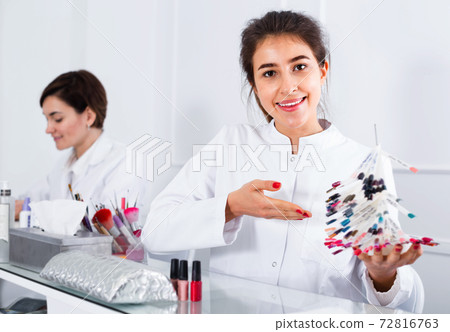 Female manicurist showing lacquer color schemes Female manicurist showing lacquer color schemes 72816763